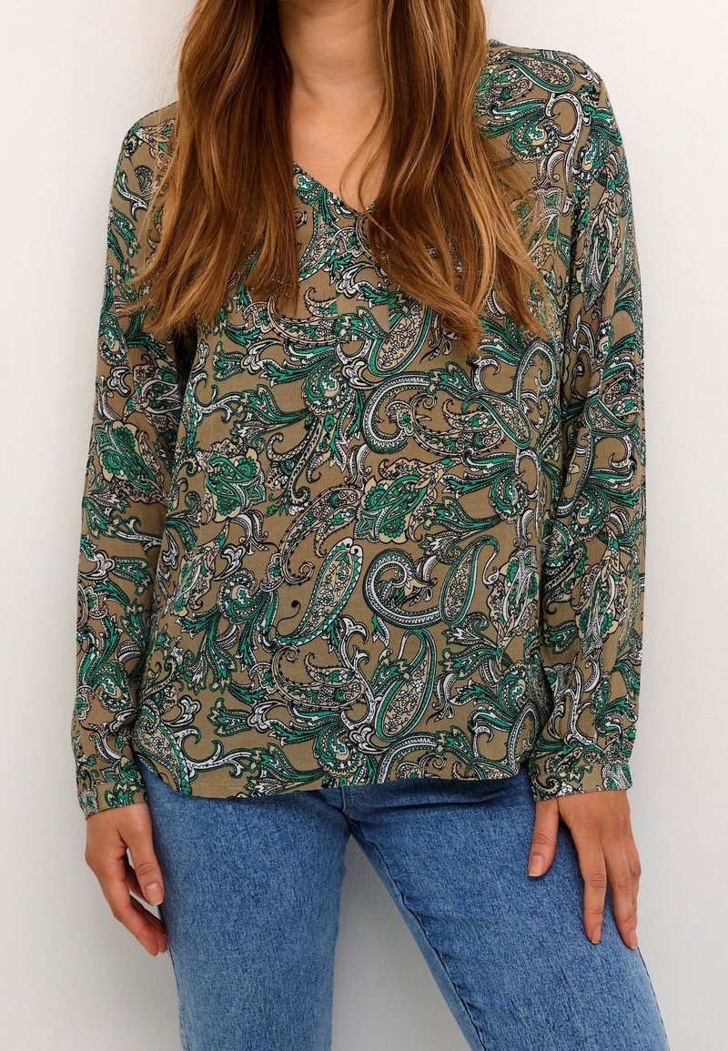 Blouse à manches longues en vert olive avec un motif cachemire dans des nuances de vert et de noir. Encolure en V avec une coupe décontractée ; tissu léger.