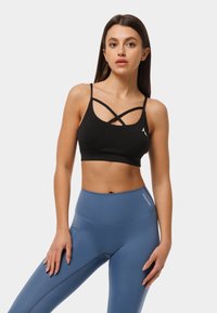 Melna sporta krūšturis ar krustveida siksnām, izgatavots no elastīga auduma. Apvienots ar augsta jostasvieta zilajām leggingām ar smalku zīmolu.