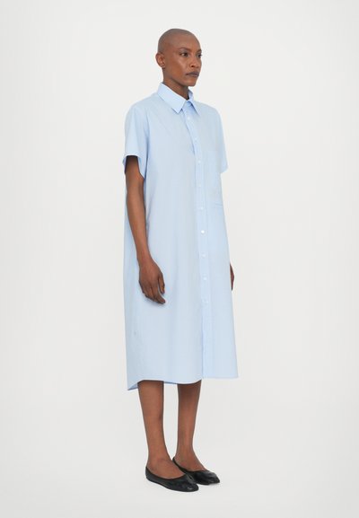 Abito camicia azzurro chiaro con maniche corte, taschino sul petto e lunghezza al ginocchio. Tessuto di morbida consistenza, vestibilità dritta.