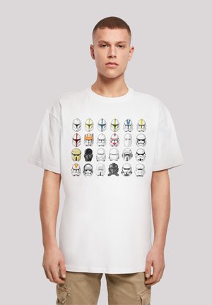 White cotton t-shirt featuring a graphic of various helmet designs in different colors arranged in rows. Relaxed fit, short sleeves.