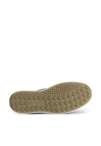 Semelle en caoutchouc avec des motifs circulaires texturés beiges, surmontée d'un dessus noir au design minimaliste. Logo estampé près du talon.