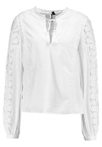 Blouse blanche avec un col rond, détail à nouer à l'avant et manches longues ornées de dentelle. Présente des motifs brodés délicats sur les manches.