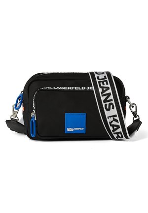 Bolso bandolera rectangular negro con bolsillo delantero, tiradores de cremallera azules, parche con logo azul y correa blanca con texto negro "KARL LAGERFELD".