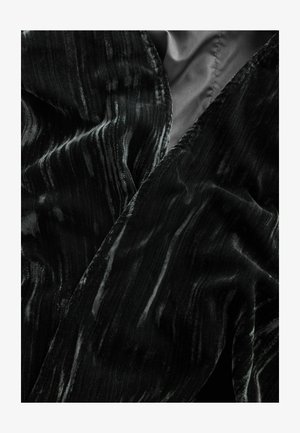 Czarna aksamitna tkanina o falistej teksturze i subtelnego blasku. Krawędzie są gładko wykończone, z bogatym wzorem jasnych i ciemnych pasków.