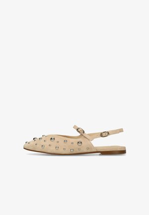 Chaussure plate slingback beige avec bout pointu, clous argentés sur la tige, et deux brides réglables avec boucles.