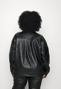 Svart läderjacka med lös passform, med mjuk textur, sänkta axlar och sydda detaljer längs ryggen.