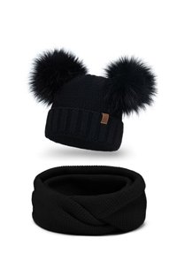 Schwarze Strickmütze mit zwei schwarzen Fell-Pompons und einem gerippten Rand. Darunter befindet sich ein passender schwarzer Strick-Infinity-Schal.