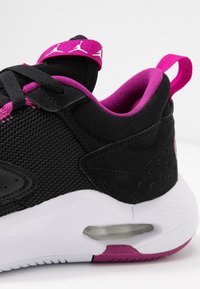 Scarpa sportiva nera e rosa con tomaia in rete e suede, suola bianca con cuscinetto d'aria visibile, linguetta di estrazione rosa e logo Jumpman sulla fascia della lingua.