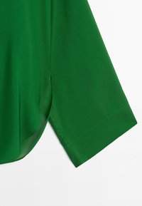 Green fabric sleeve with a side slit and a folded cuff detail against a white background.