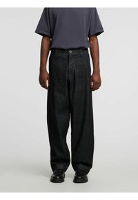 Tumši zili džinsa plataji bikses ar gludu tekstūru, priekšā aizdares pogas un dziļām kabatām. Kombinētas ar īsām pelēkas krāsas piedurknēm krekliņu.