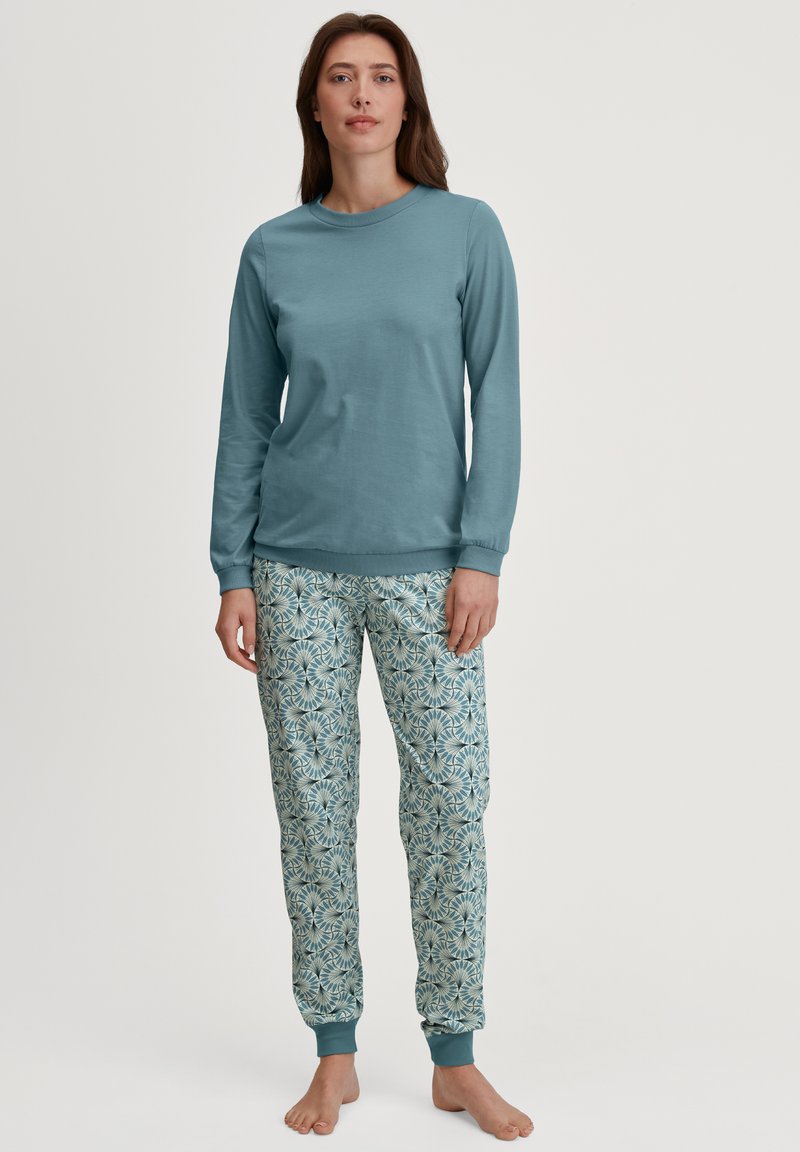 Lichtblauwe lange mouwen top gecombineerd met gestreepte pyjamabroek met een bloemenpatroon in blauw en room, met geribde manchetten.