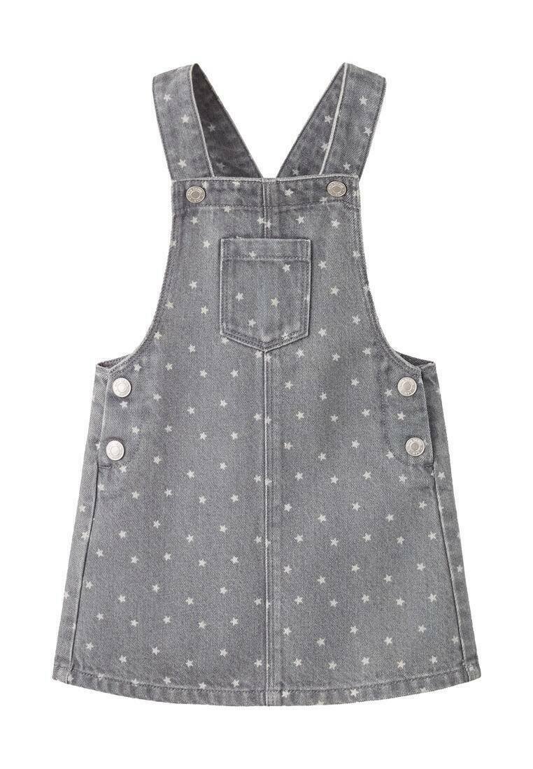 Siva traper haljina s overalls krojem, s bijelim uzorcima zvijezda, naramenicama koje se preklapaju na leđima, prednjim džepom i srebrnim gumbima sa strane.