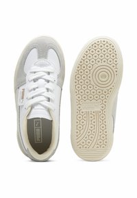 Vita och grå sneakers som har en kombination av slät läder och mocka, runda snören, en texturerad innersula och en mönstrad gummisula.