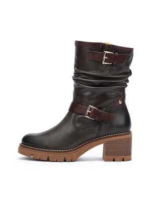 Brown leather ankle boot with a slouchy shaft, brown buckle accents, and a rugged wooden block heel, featuring a textured sole.