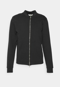 Giacca nera con zip e collo alto, realizzata in tessuto morbido. Presenta una zip frontale, polsini a coste, texture liscia e design aderente.