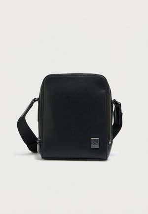 Μαύρη δερμάτινη τσάντα χιαστί με ορθογώνιο σχήμα, με κλείσιμο με φερμουάρ, ρυθμιζόμενο λουράκι και διακριτικό λογότυπο.