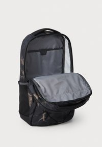 Black fabric backpack with a gray interior, zippered main compartment, and mesh side pockets; features a soft exterior pattern and adjustable straps.