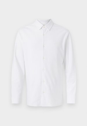 Λευκό πουκάμισο με μακριά μανίκια, κουμπιά μπροστά, μυτερό γιακά και ένα διακριτικό κεντημένο λογότυπο στο αριστερό μέρος του στήθους.