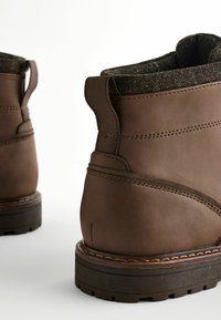 Brown leather ankle boots featuring a textured fabric lining, rounded toe, and rubber outsole with a tread pattern.
