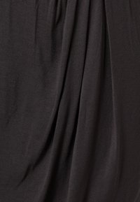 Černá tkanina s jemnou strukturou, která vykazuje splývavé záhyby a hladký povrch, čímž vytváří hladký vzhled. Žádné výrazné vzory ani kovové prvky.