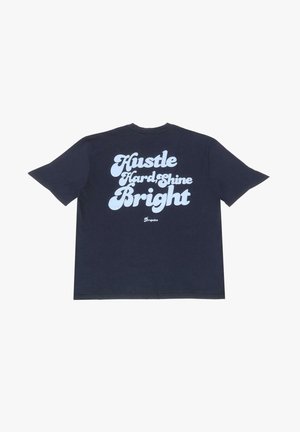 Dark navy cotton T-shirt featuring bold, white text: "Hustle Hard Shine Bright." Relaxed fit, short sleeves, and crew neckline.