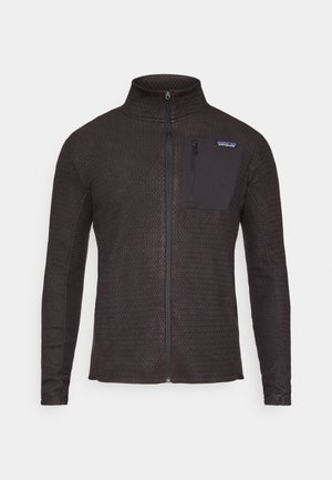 Σκούρο γκρι μπουφάν με φερμουάρ και ψηλό γιακά, υφή υφάσματος και τσέπη στο αριστερό στήθος με μαύρο φερμουάρ. Λογότυπο Patagonia στο επάνω αριστερό μέρος.