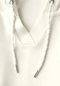 Witte hoodie met een V-halsontwerp, voorzien van gestikte trekkoorden met zilveren uiteinden en accenten. Zacht materiaal.