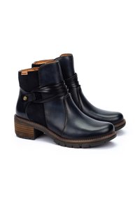 Botas de tobillo de cuero negro con una banda elástica texturizada, tacón bajo en bloque y detalles cosidos. Incluye un logo sutil en el costado.