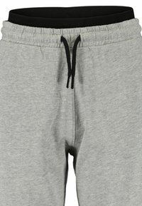 Pantalon de survêtement gris avec une taille élastique noire, un cordon de serrage ajustable et des poches latérales ; fabriqué en coton mélangé doux et texturé.