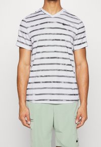 Randig kortärmad T-shirt med V-ringning i vitt med svarta horisontella linjer och texturerade detaljer. Tillverkad av lätt tyg, erbjuder den en avslappnad passform.