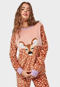 Brown fleece pajama set featuring a pink top with a deer appliqué and white polka dots, and matching pants with the same dot pattern.