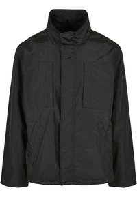 Chaqueta negra ligera con cuello alto, dos bolsillos frontales de parche y un diseño limpio y minimalista con una textura suave.
