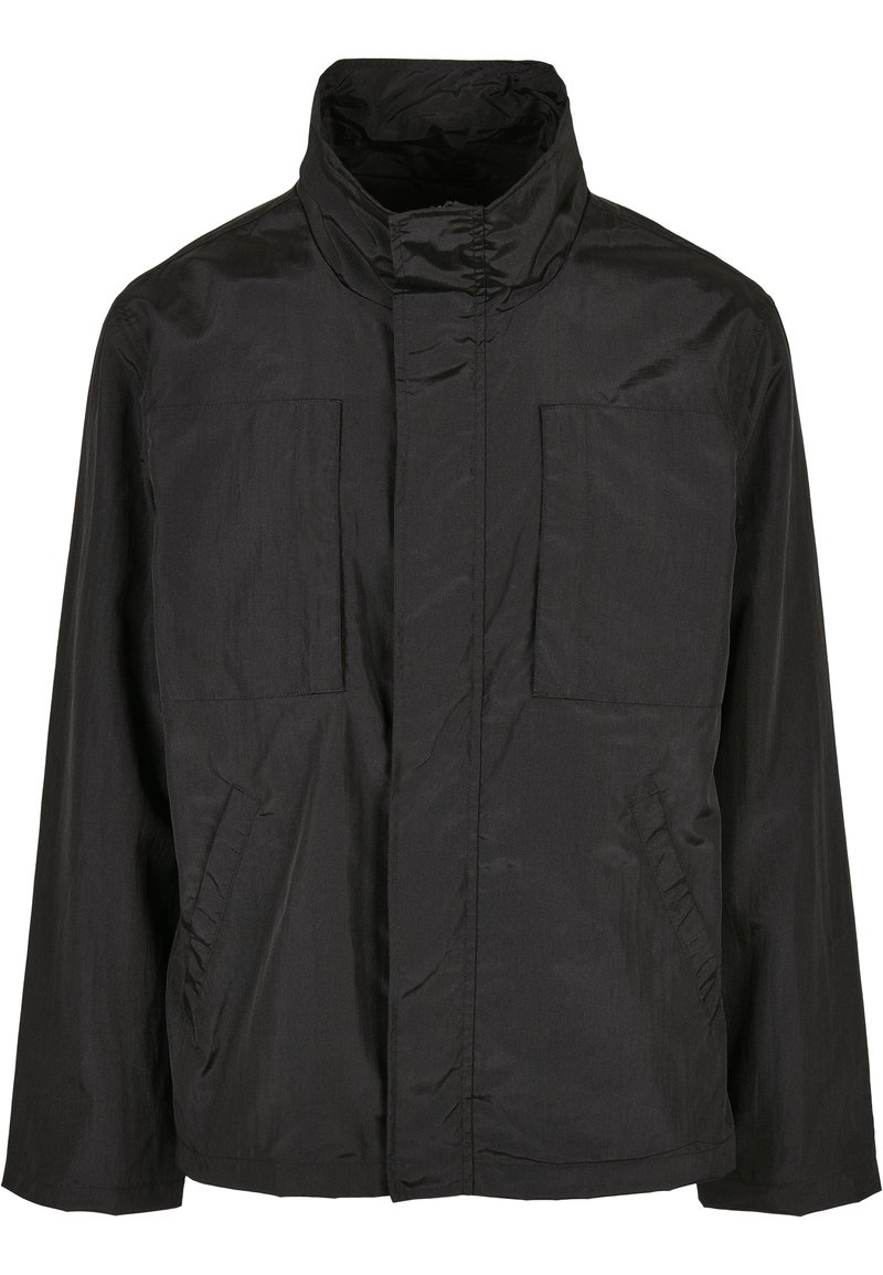 Chaqueta negra ligera con cuello alto, dos bolsillos frontales de parche y un diseño limpio y minimalista con una textura suave.