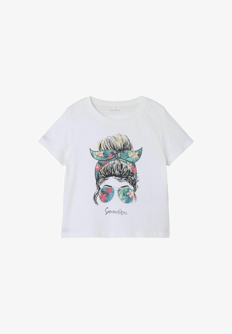 Balta kokvilnas t-krekls ar grafisku dizainu, kurā attēlota sieviete ar bun un ziedu galvassegu, kas valkā saulesbrilles, ar tropiskiem lapu un ziedu motīviem.