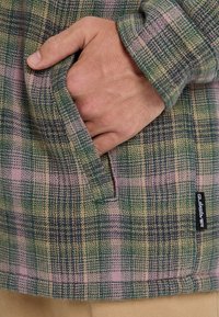 Karierte Flanelljacke in Grün-, Pink- und Gelbtönen. Verfügt über eine Fronttasche und ein gewebtes Etikett. Weiche Textur mit lockerem Schnitt.