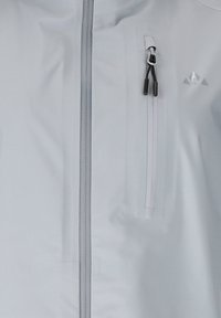 Lichtgrijze jas aan de voorkant met verticale ritssluiting en een klein borstzakje met rits, voorzien van twee zwarte trekkoorden.