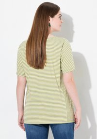 Camiseta de rayas verdes con mangas cortas y corte recto, hecha de una tela suave. Las rayas están espaciadas uniformemente y son delgadas.