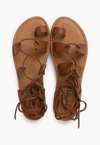 Sandali in pelle marrone con diversi design di cinghie, dotati di una suola piatta e lacci annodati. Texture liscia e design semplice e aperto per la traspirabilità.