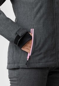 Graue Outerwear mit weichem Material, pinken Reißverschlussakzenten und einer seitlichen Reißverschlusstasche mit Klettverschlussdetails an den Bündchen.