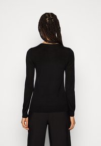 Czarny sweter z długim rękawem, wykonany z lekkiego dzianiny, z okrągłym dekoltem i ściągaczami na rękawach, zaprojektowany w dopasowanej sylwetce.