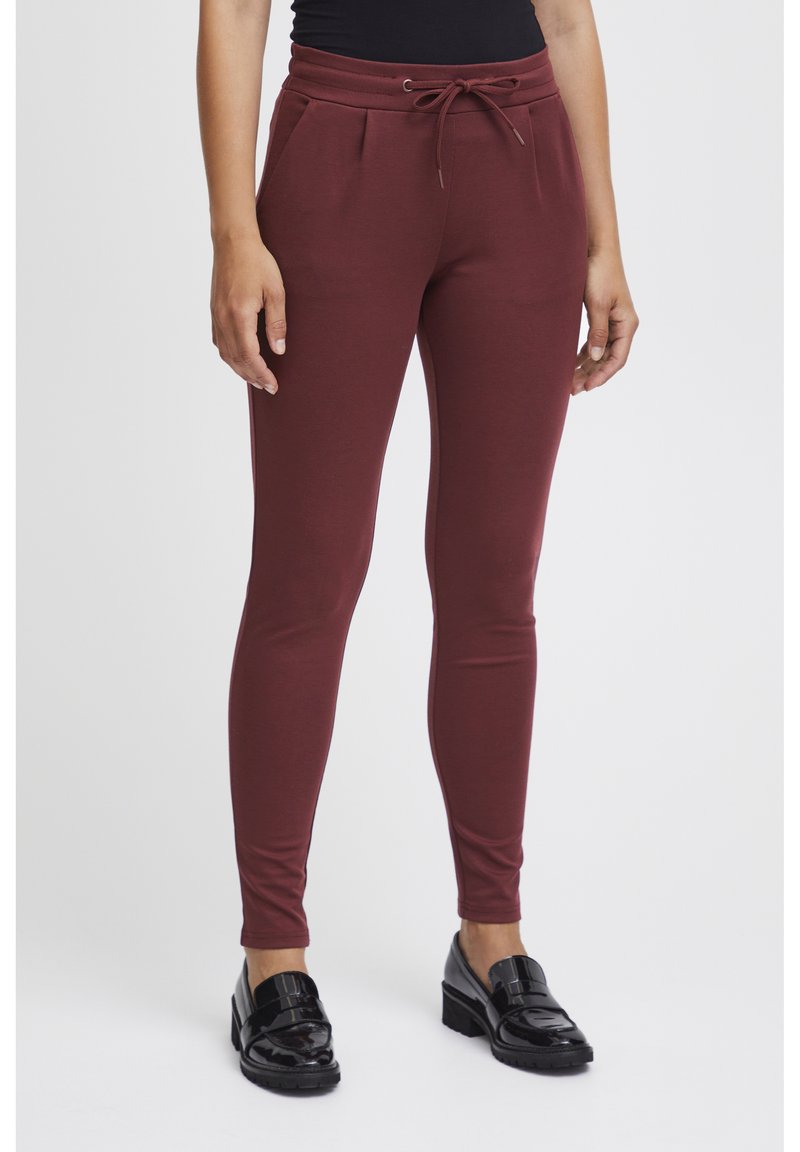 Burgundyröda joggerbyxor med resårmidja och justerbar dragsko. Slim fit, mjuk textur och sidfickor. Matchas med svarta loafers.