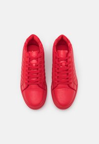 Rote Leder-Sneaker mit glatter Textur, ausgestattet mit einem Schnürdesign, gepolstertem Kragen und schrägen Steppakzenten an den Seiten.