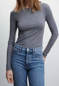 Gray long-sleeve ribbed top paired with high-waisted light blue denim jeans. The fabric appears soft with a fitted design and standard neckline.
