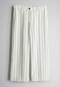 Witte broek met zwarte verticale krijtstrepen, elastische tailleband en bruine knoopsluiting, afgebeeld tegen een grijze achtergrond.