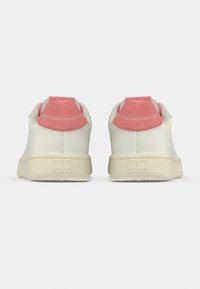Άσπρα αθλητικά παπούτσια με λείο δερμάτινο φινίρισμα, ροζ σουέντ λεπτομέρειες στη φτέρνα και υφή στη μπεζ καουτσούκ σόλα με ανάγλυφο λογότυπο.