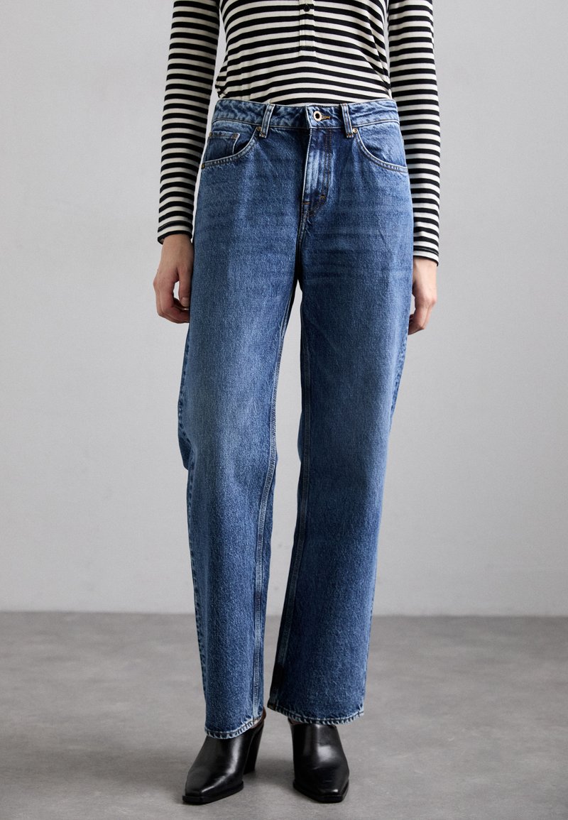Höga, ljusblå jeans med rak passform, tillverkade av denim. Har fem fickor, en framknapp och uppvikta fållar.