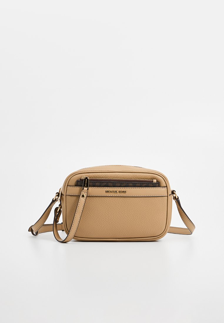 Pequeño bolso cruzado de cuero marrón claro con un bolsillo con cremallera en la parte frontal, correa ajustable y el logotipo dorado de Michael Kors en la parte delantera.