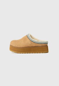 Tan slip-on klogs med en teksturert semsket overdel, en myk fôring og en fargerik vevd detalj rundt kragen. Tykk plattformsåle.