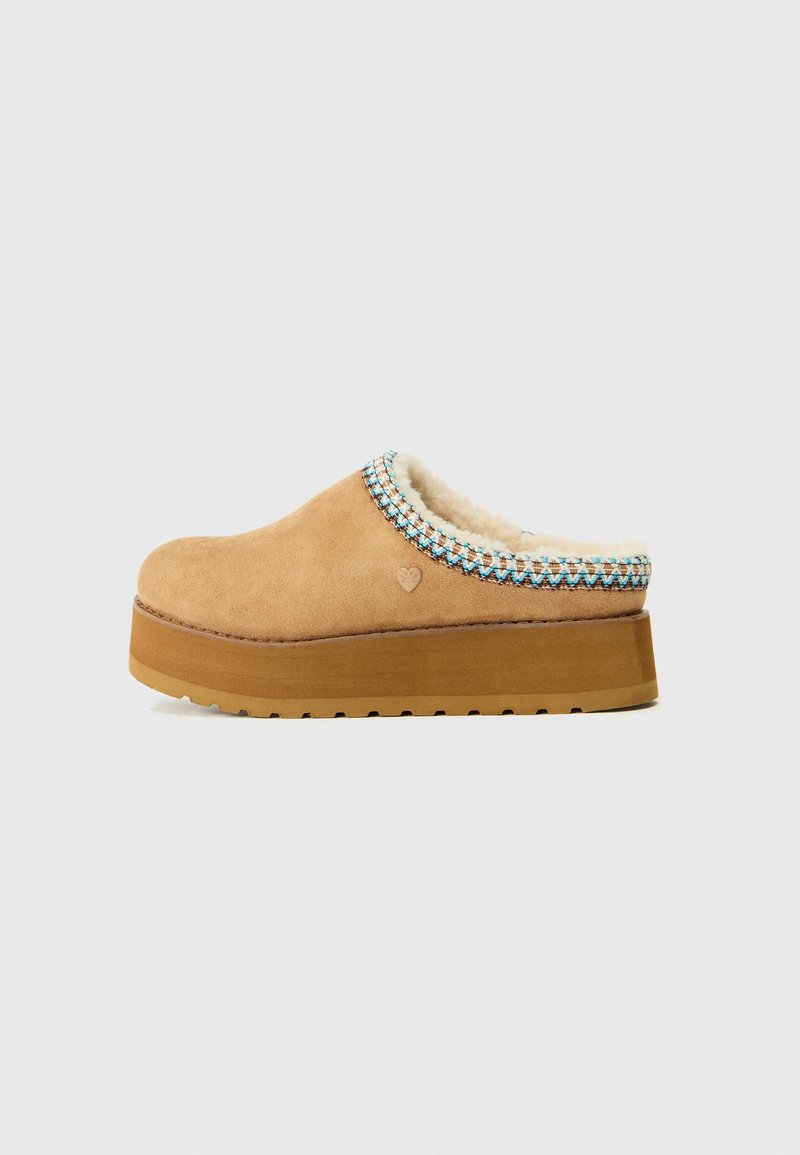Tan slip-on klogs med en teksturert semsket overdel, en myk fôring og en fargerik vevd detalj rundt kragen. Tykk plattformsåle.