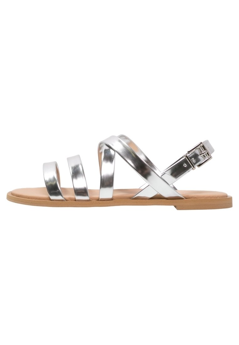 Sandali in metallo argento con cinturini, dotati di una suola piatta color tan, caratterizzati da tre cinturini larghi e una chiusura con fibbia per una vestibilità regolabile.
